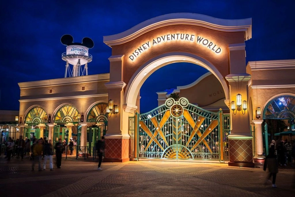 Entrance to Disney Adventure World at Disneyland® Paris, with its illuminated gate at night.