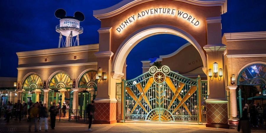 Entrance to Disney Adventure World at Disneyland® Paris, with its illuminated gate at night.