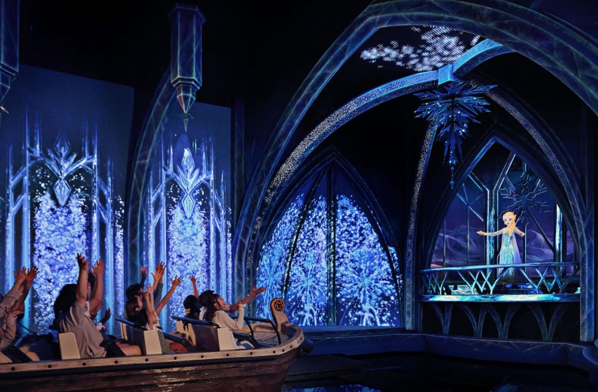 Visitors on the Frozen Ever After attraction, facing Elsa in World of Frozen at Disney Adventure World.